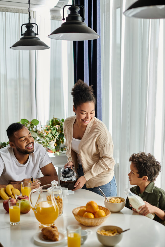 African american family having breakfast around white table\.